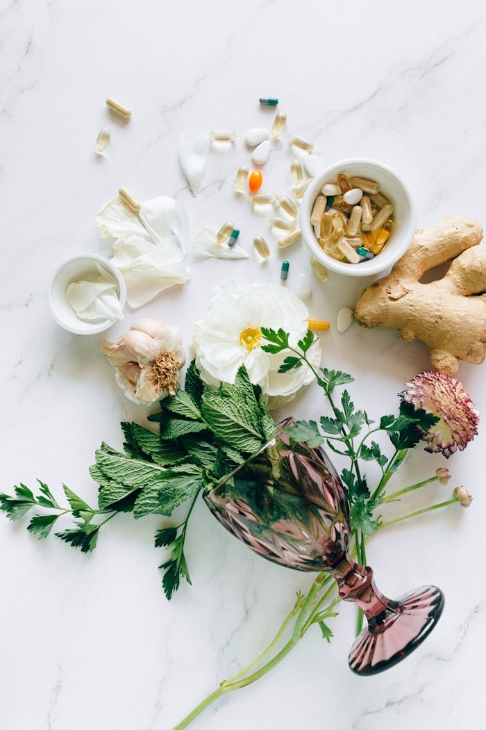 Flat lay of herbs, supplements, and ginger on a marble surface, representing natural healthcare.